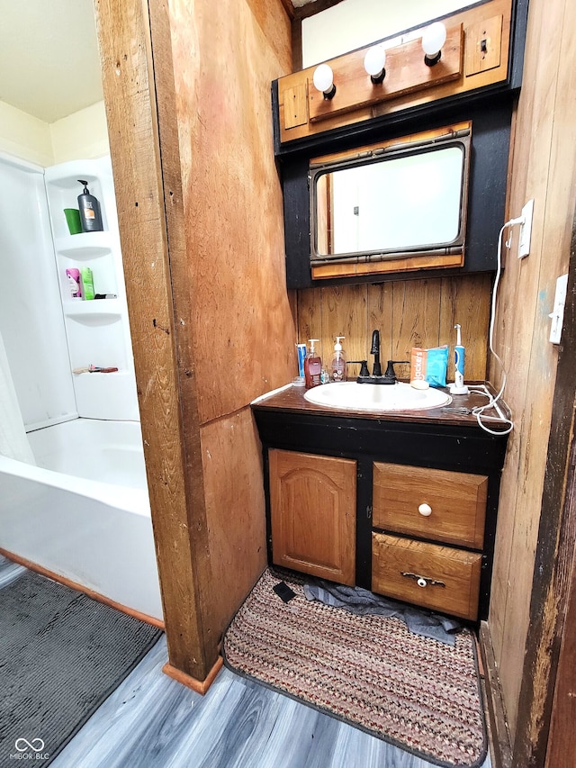 bathroom featuring vanity, hardwood / wood-style floors, and wooden walls