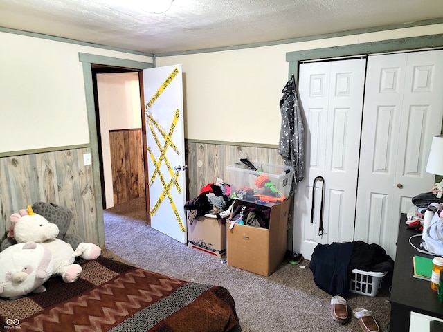 bedroom featuring a textured ceiling, carpet floors, a closet, and wood walls