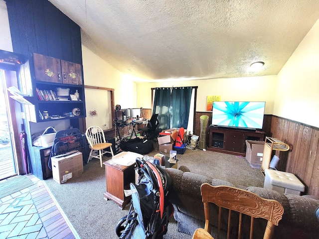 living room with lofted ceiling, a textured ceiling, wooden walls, and carpet floors