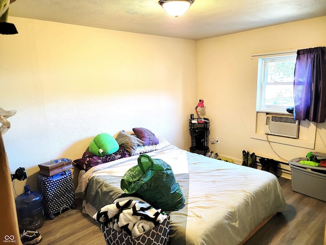 bedroom featuring cooling unit, hardwood / wood-style floors, and a textured ceiling