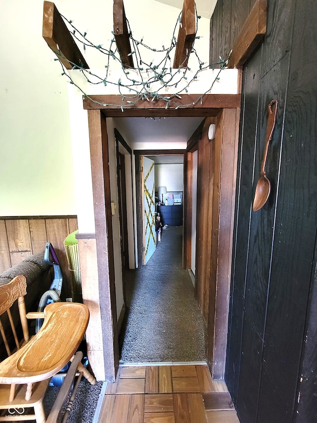 hallway featuring wooden walls and carpet