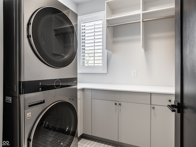 laundry area with stacked washer and clothes dryer and cabinets