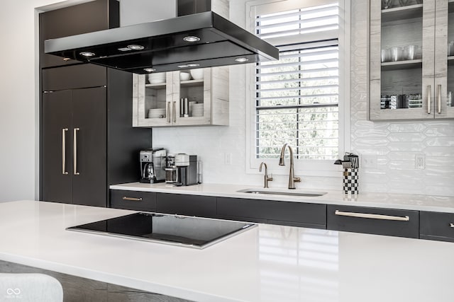 kitchen with island exhaust hood, decorative backsplash, sink, and black electric cooktop