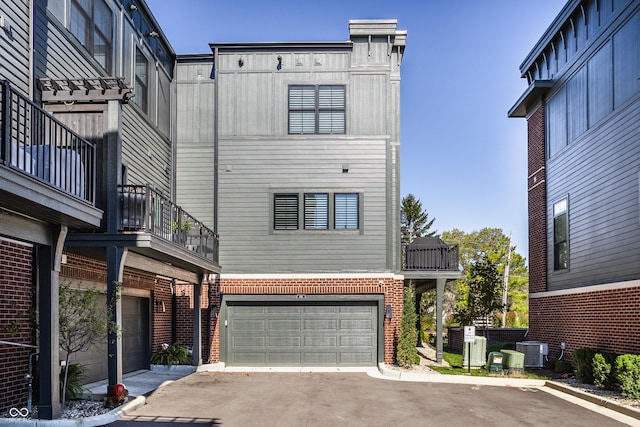 456 Monon Way Dr, Carmel, IN 46032 - view of front of house with central AC unit, a balcony, aphalt driveway, a garage, and brick siding