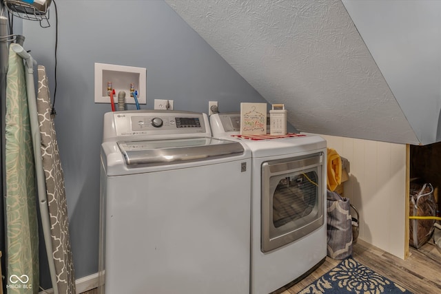 laundry room with a textured ceiling, washing machine and clothes dryer, and hardwood / wood-style floors