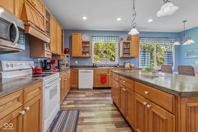 kitchen featuring a kitchen island, light wood-type flooring, sink, decorative light fixtures, and white appliances