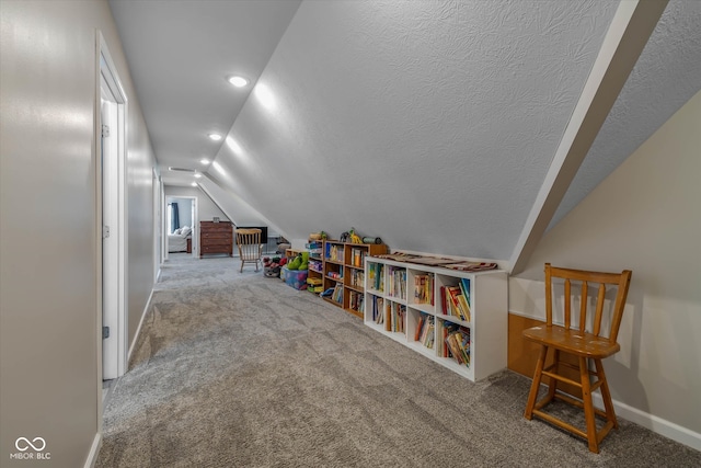 recreation room with a textured ceiling, carpet flooring, and vaulted ceiling