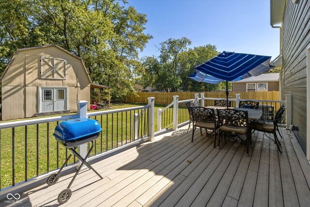 wooden terrace featuring a storage unit, grilling area, and a lawn