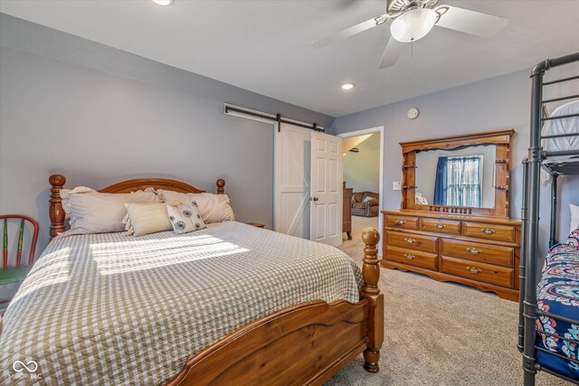 carpeted bedroom featuring a barn door and ceiling fan