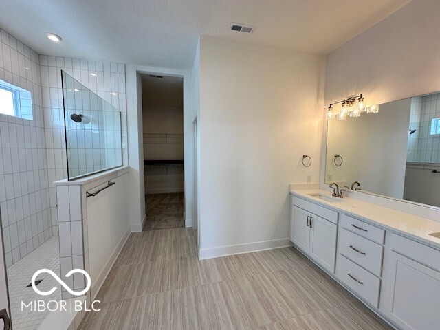 bathroom featuring vanity and tiled shower