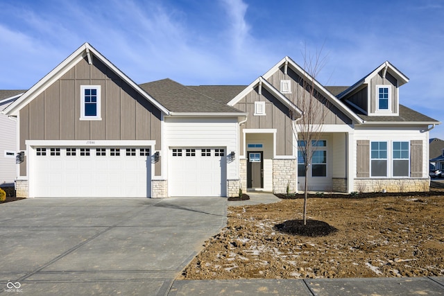 view of front of house featuring stone siding, an attached garage, roof with shingles, board and batten siding, and driveway