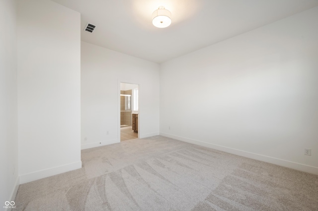 spare room with light carpet, baseboards, and visible vents