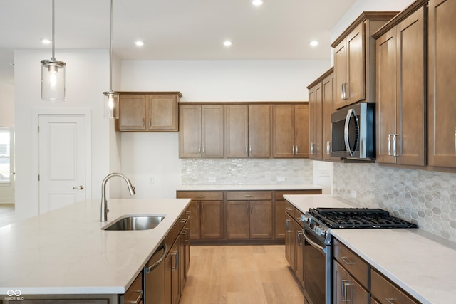 kitchen featuring a sink, decorative light fixtures, brown cabinets, and appliances with stainless steel finishes