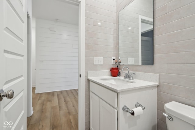 10008 Sundley Dr, Indianapolis, IN 46239 - half bath featuring toilet, wooden walls, vanity, and wood finished floors