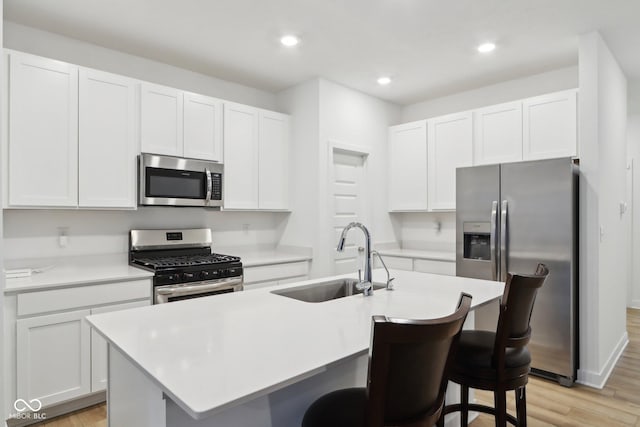 10008 Sundley Dr, Indianapolis, IN 46239 - kitchen with a kitchen island with sink, stainless steel appliances, white cabinetry, a sink, and a breakfast bar area