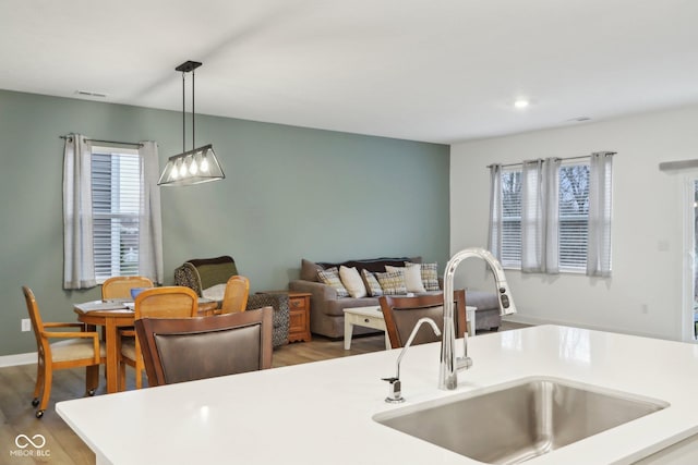 10008 Sundley Dr, Indianapolis, IN 46239 - kitchen featuring light countertops, a sink, pendant lighting, baseboards, and light wood-style floors