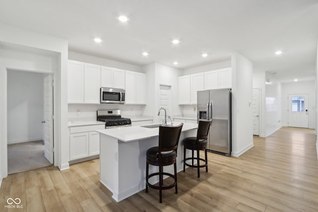 10008 Sundley Dr, Indianapolis, IN 46239 - kitchen featuring white cabinetry, a sink, light wood-style floors, an island with sink, and appliances with stainless steel finishes