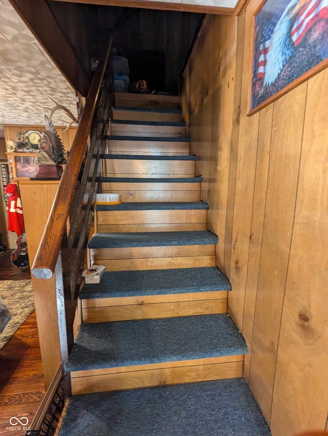 staircase featuring wood walls