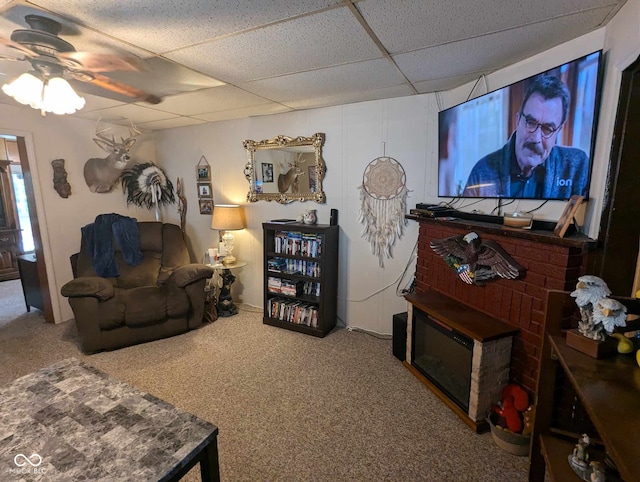 carpeted living room featuring a drop ceiling and ceiling fan