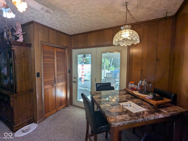 dining area featuring light carpet and wood walls