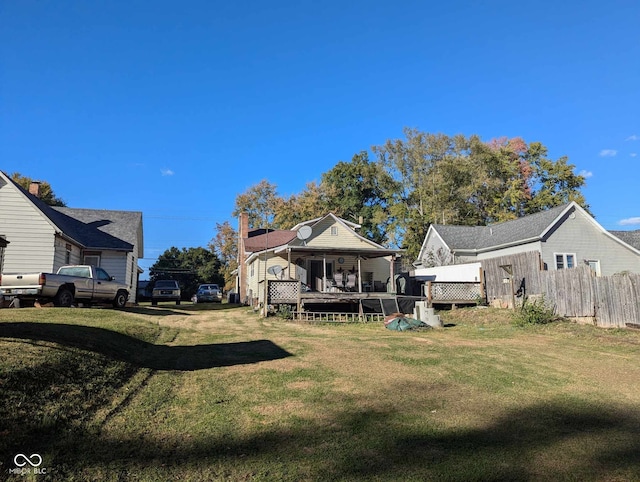 rear view of property featuring a wooden deck and a lawn