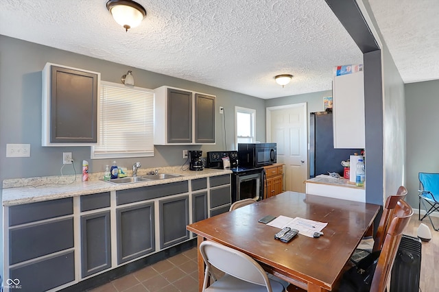 kitchen with stainless steel refrigerator, sink, range with electric stovetop, and gray cabinetry