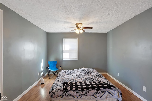 bedroom with ceiling fan, a textured ceiling, and hardwood / wood-style floors