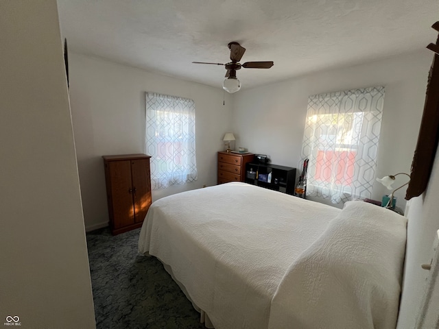 bedroom with ceiling fan and dark colored carpet