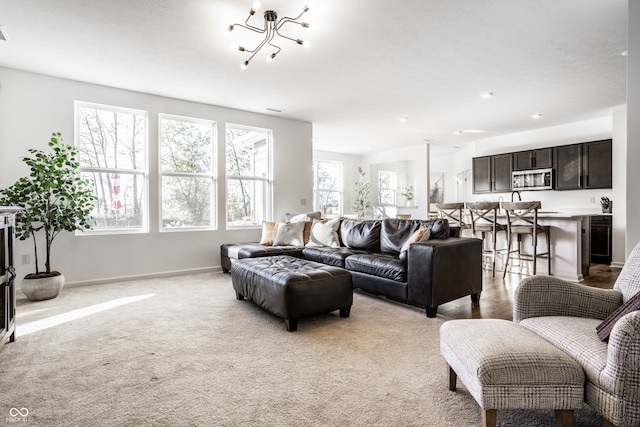 living room featuring light carpet, a notable chandelier, and a wealth of natural light