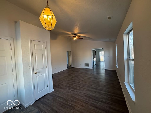 unfurnished living room featuring dark wood-type flooring, ceiling fan, vaulted ceiling, and a textured ceiling