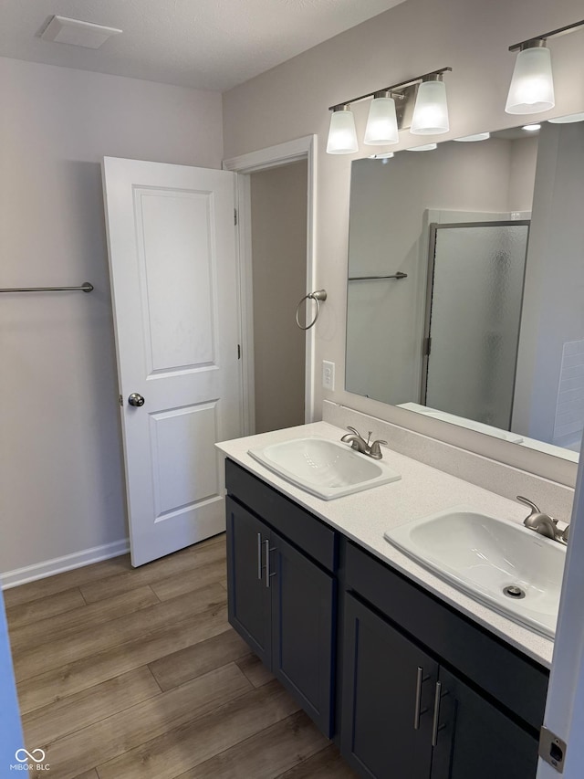 bathroom with wood-type flooring, vanity, and a shower with door