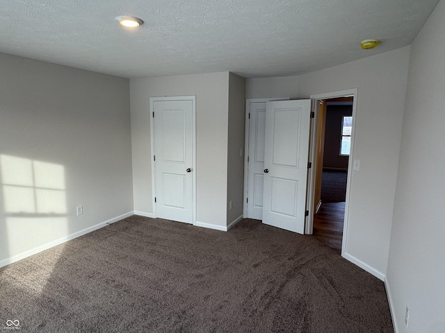 unfurnished bedroom with a closet, dark carpet, and a textured ceiling