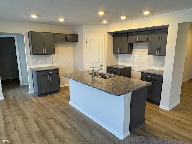 kitchen with backsplash, sink, an island with sink, and hardwood / wood-style flooring