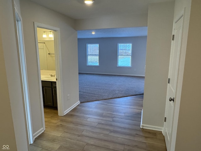 hallway with light hardwood / wood-style floors and sink