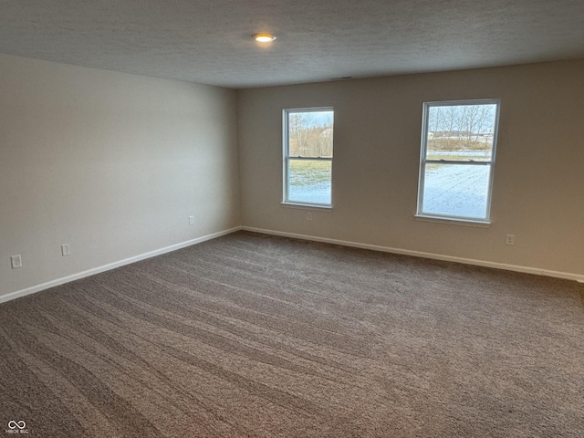 unfurnished room featuring a textured ceiling and dark carpet