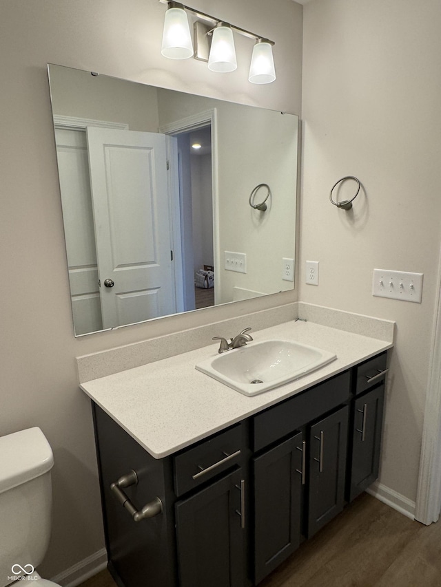 bathroom featuring wood-type flooring, vanity, and toilet