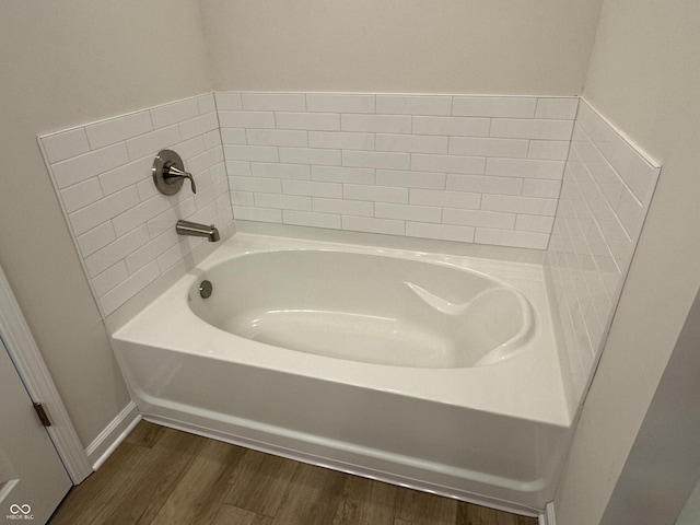 bathroom with hardwood / wood-style floors and a tub to relax in