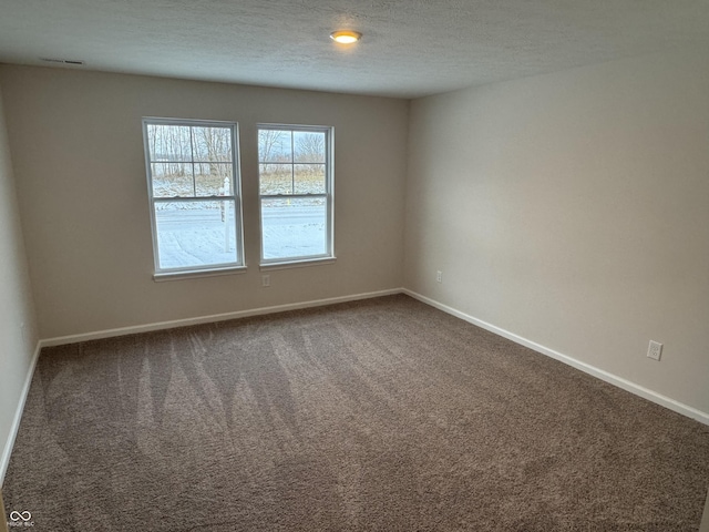 carpeted empty room featuring a textured ceiling