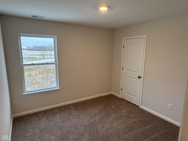 unfurnished room featuring dark colored carpet, plenty of natural light, and a textured ceiling