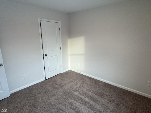 spare room featuring dark carpet