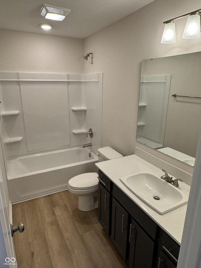 full bathroom featuring hardwood / wood-style floors, vanity, shower / bath combination, and toilet