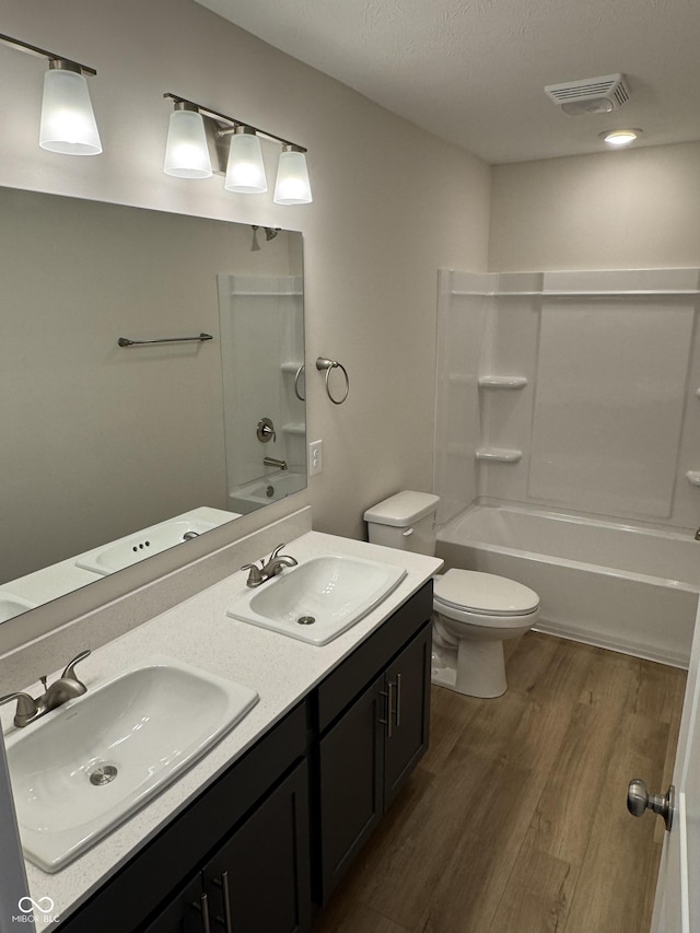 full bathroom featuring washtub / shower combination, hardwood / wood-style floors, vanity, and toilet