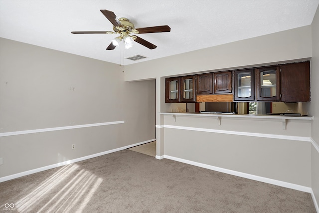 kitchen featuring kitchen peninsula, dark brown cabinetry, carpet floors, and ceiling fan