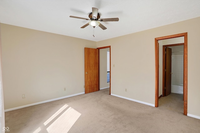 unfurnished bedroom featuring ensuite bath, light colored carpet, and ceiling fan