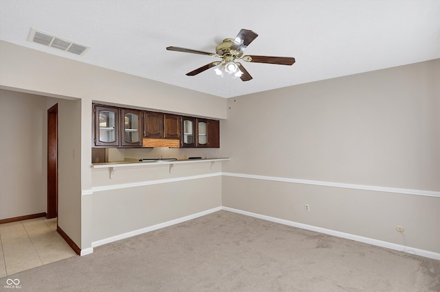 kitchen with ceiling fan, dark brown cabinetry, kitchen peninsula, and light colored carpet