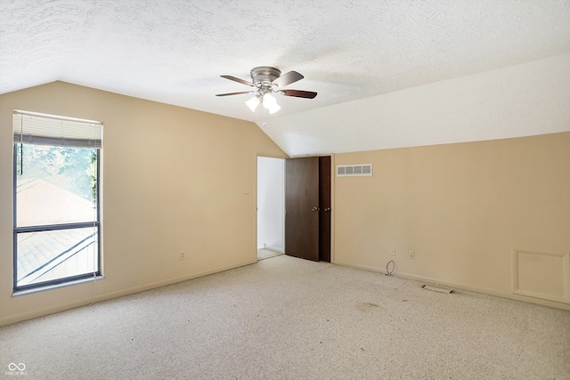 carpeted spare room with ceiling fan, a textured ceiling, and vaulted ceiling