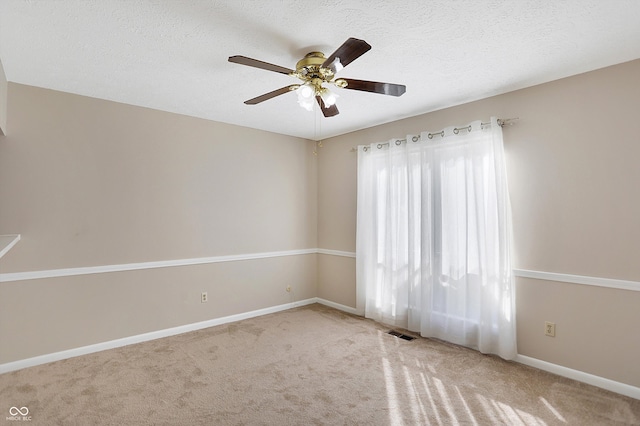 carpeted empty room with ceiling fan and a textured ceiling