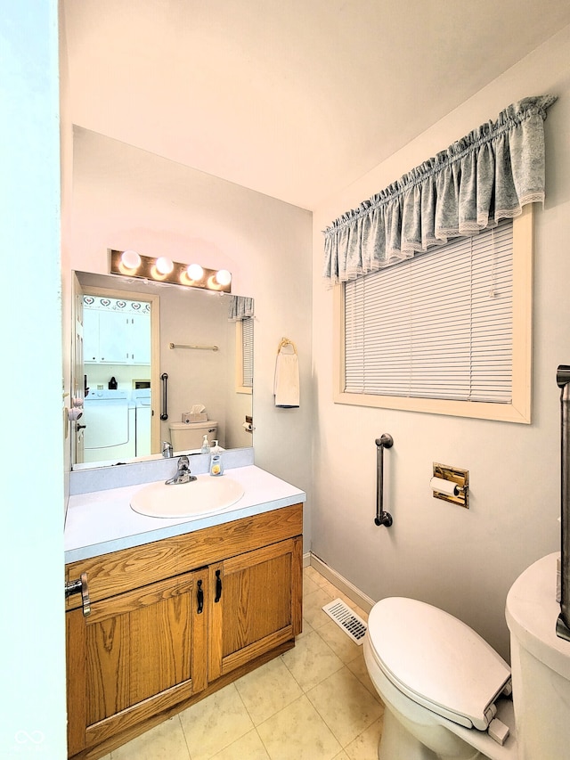 bathroom featuring vanity, washing machine and clothes dryer, toilet, and tile patterned flooring