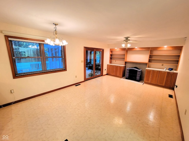 unfurnished living room with ceiling fan with notable chandelier