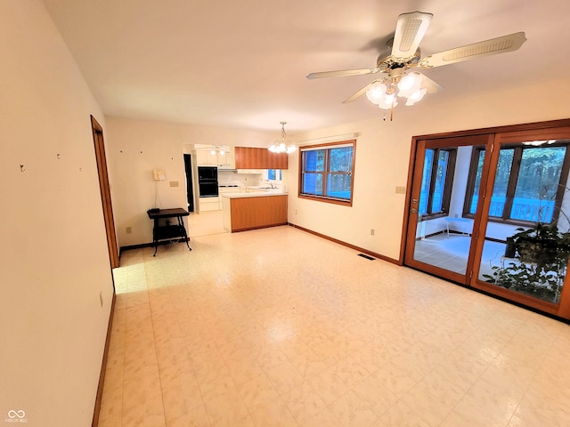 unfurnished living room featuring sink and ceiling fan with notable chandelier